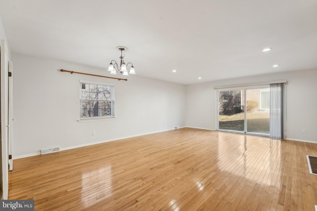 unfurnished living room featuring a healthy amount of sunlight, a chandelier, and light wood-type flooring