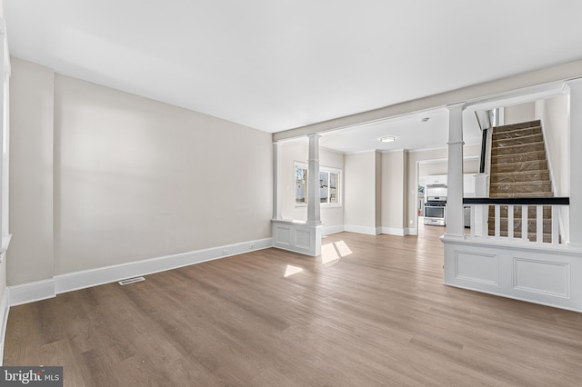 unfurnished living room with decorative columns and light hardwood / wood-style flooring