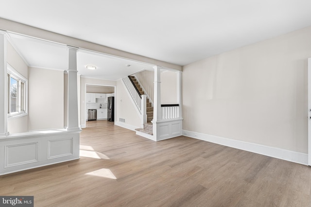 unfurnished living room featuring light wood-type flooring and ornate columns