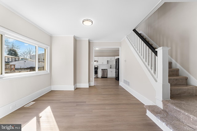 foyer entrance featuring crown molding, sink, and light hardwood / wood-style flooring