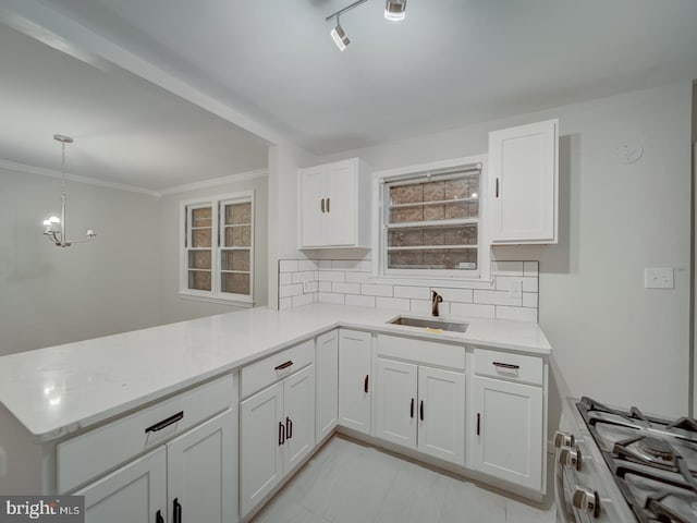 kitchen with gas range, white cabinetry, kitchen peninsula, and sink