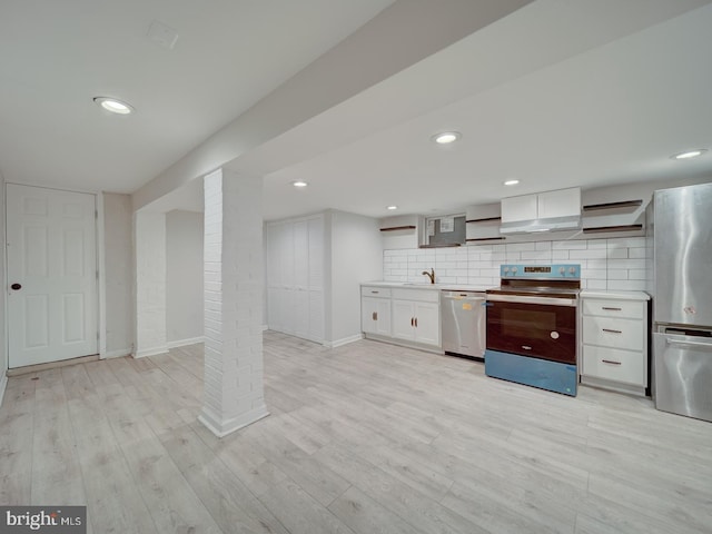 kitchen with appliances with stainless steel finishes, white cabinetry, sink, light hardwood / wood-style floors, and wall chimney exhaust hood