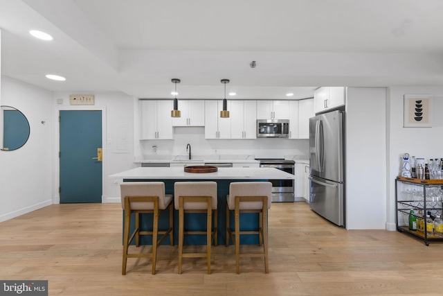 kitchen featuring sink, white cabinetry, appliances with stainless steel finishes, a kitchen island, and pendant lighting