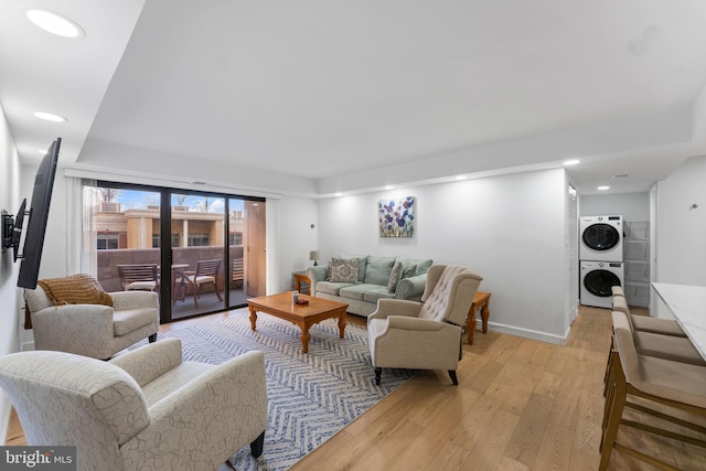 living room with light hardwood / wood-style floors and stacked washing maching and dryer