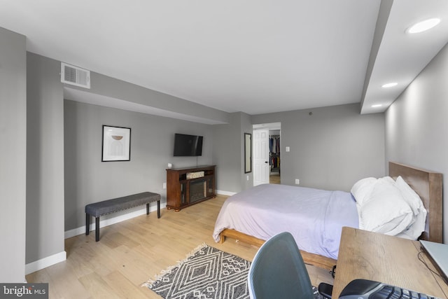 bedroom with a fireplace and light wood-type flooring