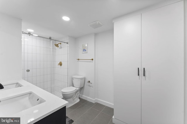 bathroom featuring vanity, a tile shower, tile patterned floors, and toilet