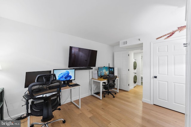 office space with stacked washer / dryer and light hardwood / wood-style flooring