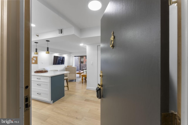 kitchen featuring hanging light fixtures, white cabinetry, and light hardwood / wood-style flooring