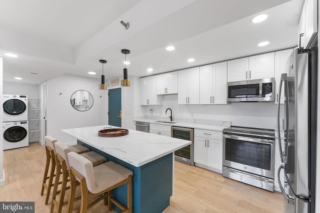 kitchen featuring sink, appliances with stainless steel finishes, a center island, stacked washer / dryer, and wine cooler