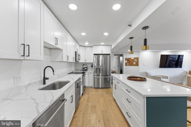 kitchen with pendant lighting, white cabinetry, sink, light stone counters, and stainless steel appliances