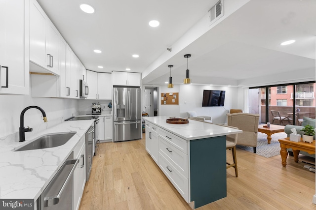 kitchen featuring white cabinetry, sink, a kitchen island, and appliances with stainless steel finishes