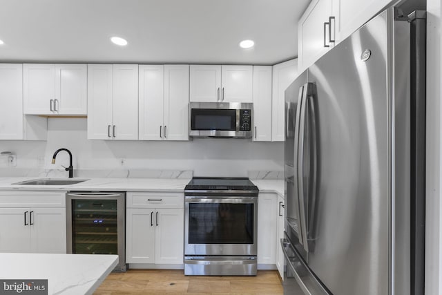 kitchen with wine cooler, sink, white cabinetry, and stainless steel appliances