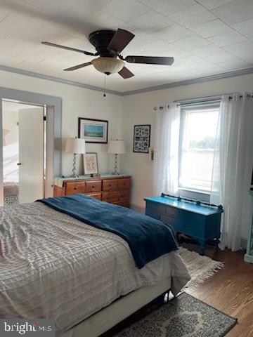 bedroom with ornamental molding, hardwood / wood-style floors, and ceiling fan