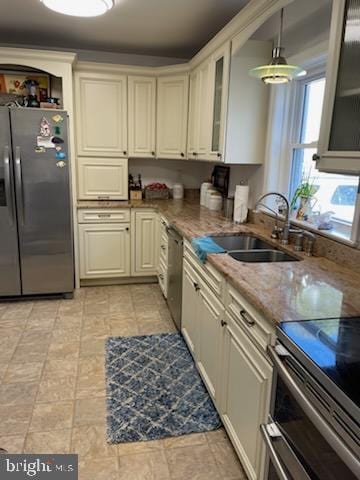 kitchen featuring sink, decorative light fixtures, stainless steel appliances, and dark stone counters