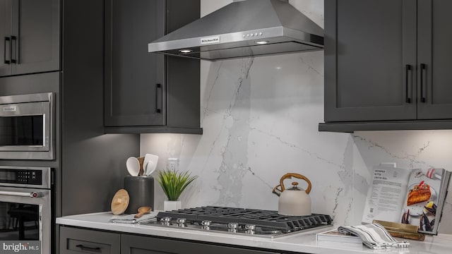 kitchen with wall chimney range hood, backsplash, and stainless steel appliances