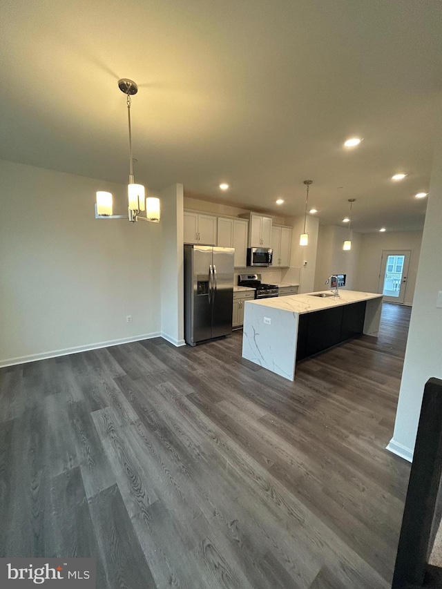 kitchen with stainless steel appliances, a kitchen island with sink, white cabinets, and decorative light fixtures