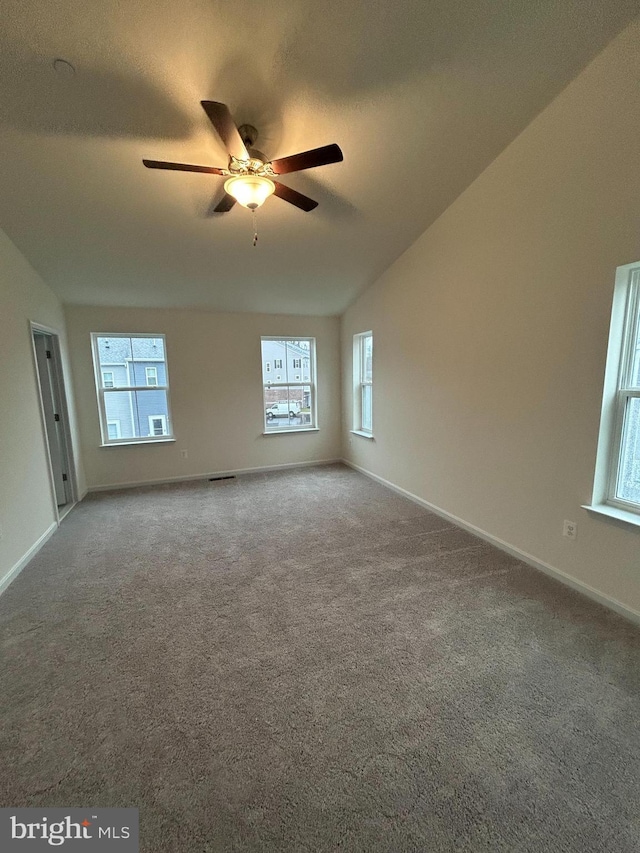 empty room with vaulted ceiling, ceiling fan, and carpet flooring