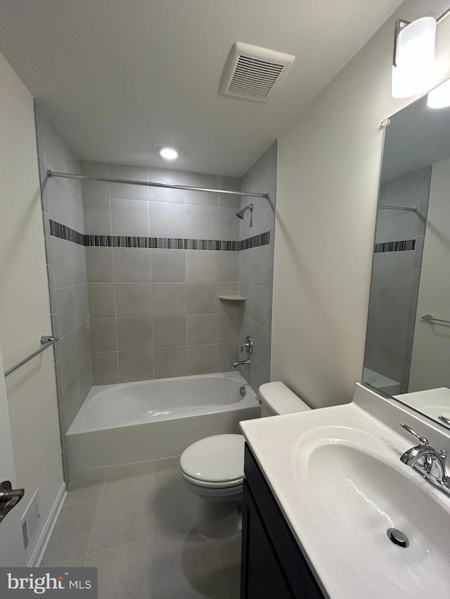 full bathroom featuring tile patterned flooring, vanity, tiled shower / bath, and toilet