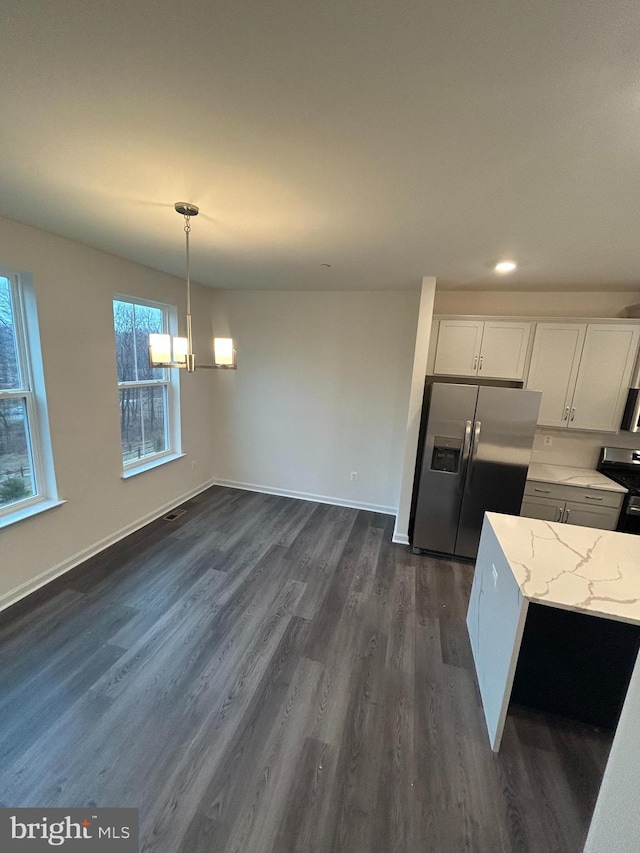 kitchen featuring pendant lighting, stainless steel appliances, dark hardwood / wood-style floors, light stone countertops, and white cabinets