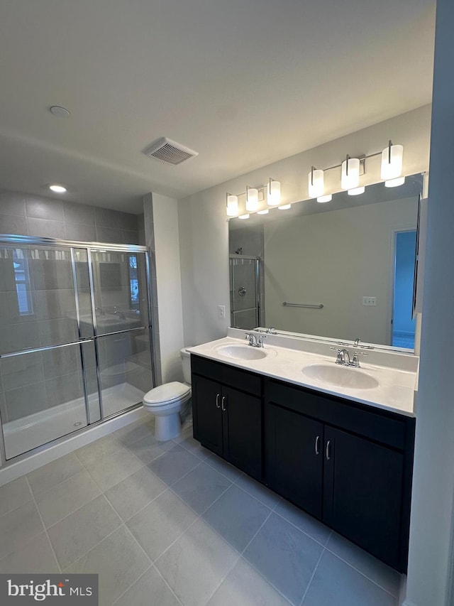 bathroom with a shower with door, vanity, tile patterned floors, and toilet