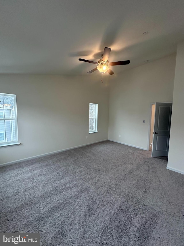 carpeted spare room featuring vaulted ceiling and ceiling fan