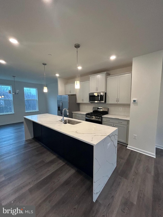 kitchen featuring dark wood-type flooring, sink, hanging light fixtures, appliances with stainless steel finishes, and a large island