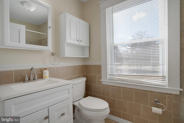 bathroom featuring vanity, tile walls, and toilet