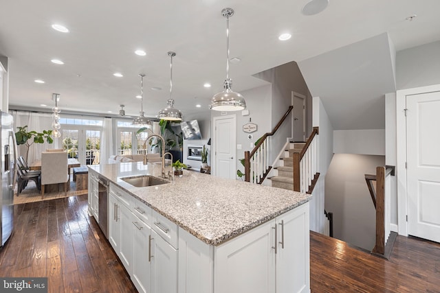 kitchen featuring white cabinets, light stone countertops, a kitchen island with sink, a sink, and recessed lighting