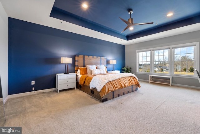 carpeted bedroom featuring recessed lighting, a raised ceiling, and baseboards