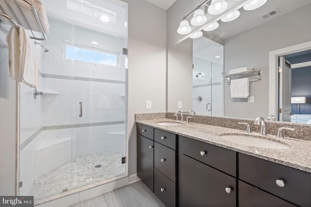 bathroom featuring visible vents, a sink, a shower stall, and double vanity