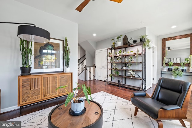 sitting room with ceiling fan, stairway, and wood finished floors