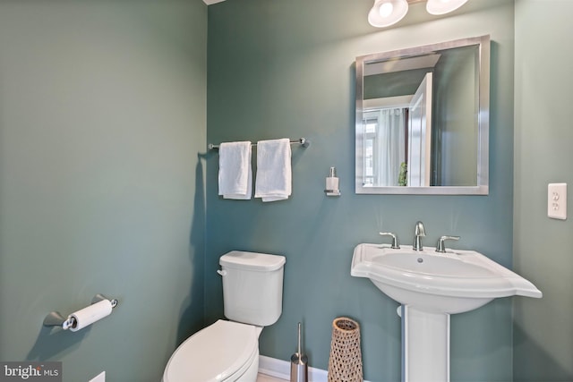 bathroom with baseboards, a sink, and toilet