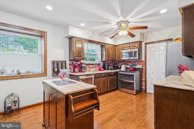 kitchen with sink, decorative backsplash, appliances with stainless steel finishes, and light hardwood / wood-style floors