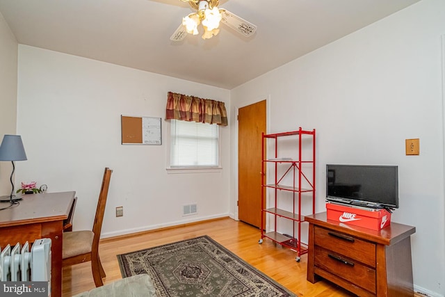 home office with hardwood / wood-style flooring, ceiling fan, and radiator