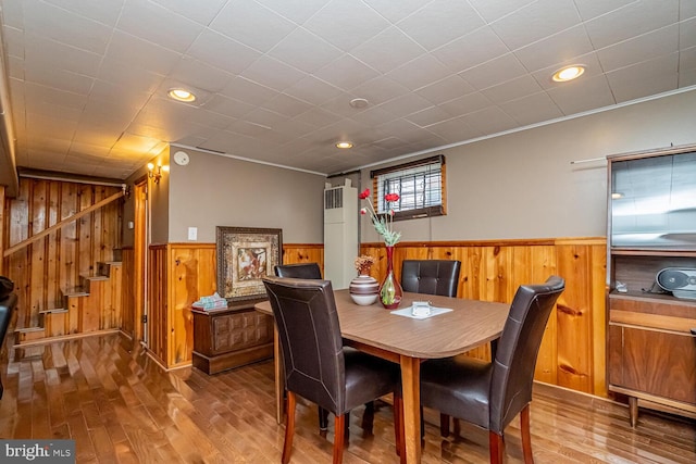 dining room featuring wood-type flooring and wood walls