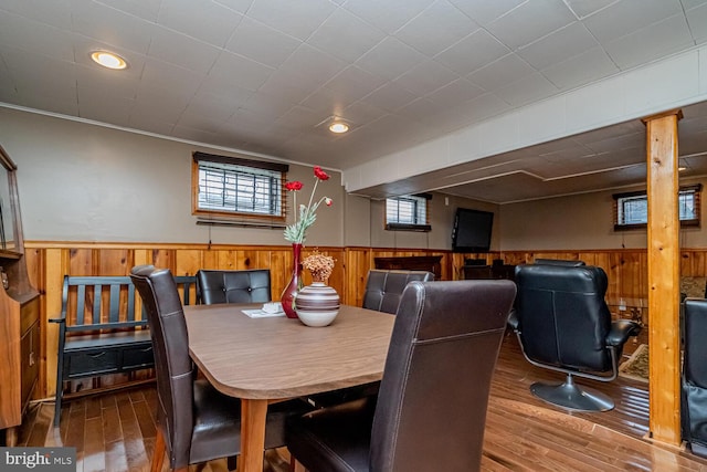 dining room with hardwood / wood-style flooring and wood walls