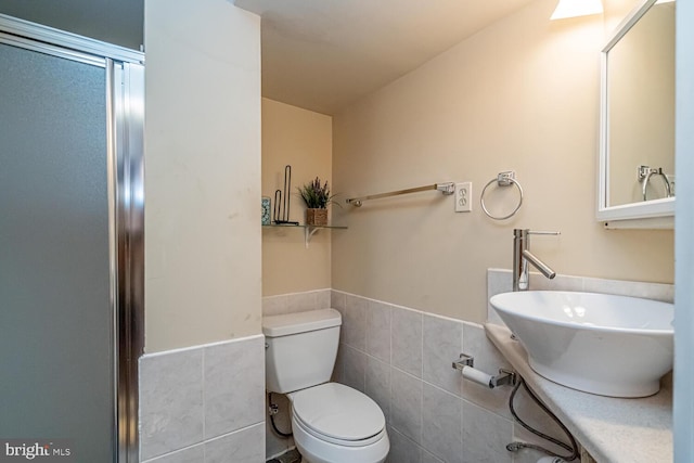 bathroom with toilet, sink, and tile walls