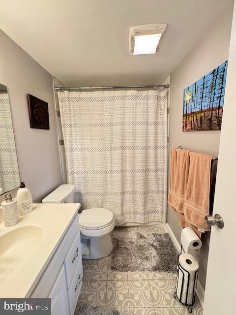 bathroom with vanity, toilet, curtained shower, and tile patterned flooring