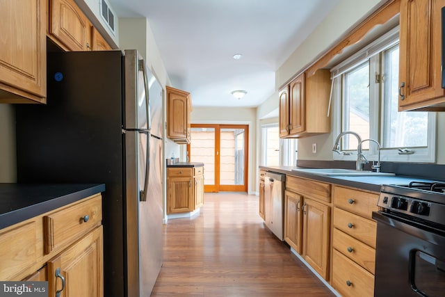 kitchen featuring stainless steel appliances, wood-type flooring, and sink