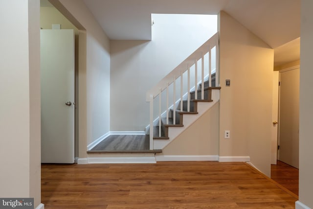 staircase with lofted ceiling and wood-type flooring