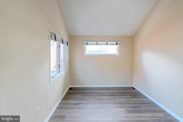 empty room with light hardwood / wood-style floors and vaulted ceiling