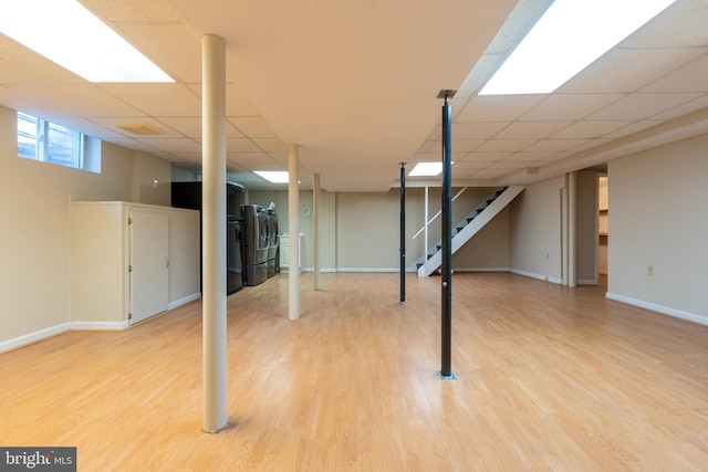 basement with wood-type flooring, a paneled ceiling, and washing machine and dryer