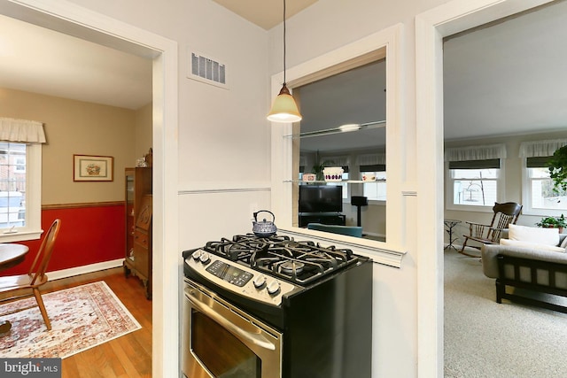 kitchen with stainless steel gas stove, visible vents, a wealth of natural light, and wood finished floors