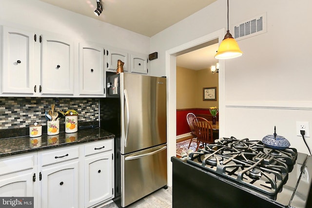 kitchen with visible vents, dark stone counters, decorative backsplash, freestanding refrigerator, and white cabinetry