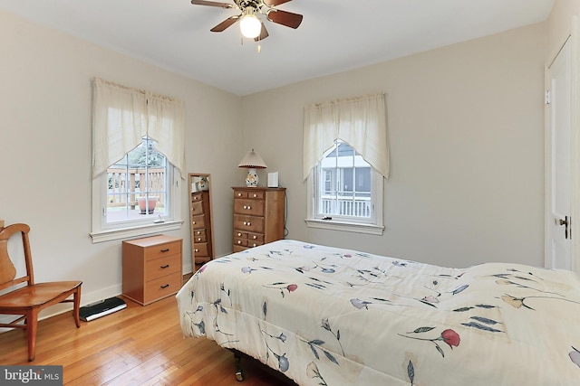 bedroom with light wood finished floors, multiple windows, and baseboards