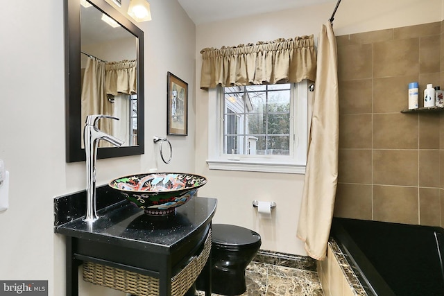 full bath with a sink, toilet, and a tile shower