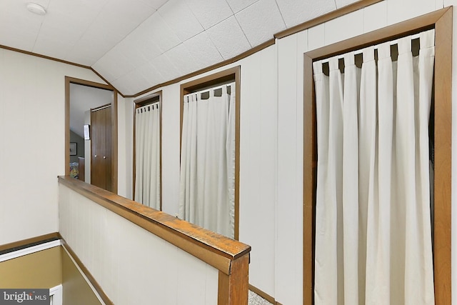 hallway with vaulted ceiling and crown molding