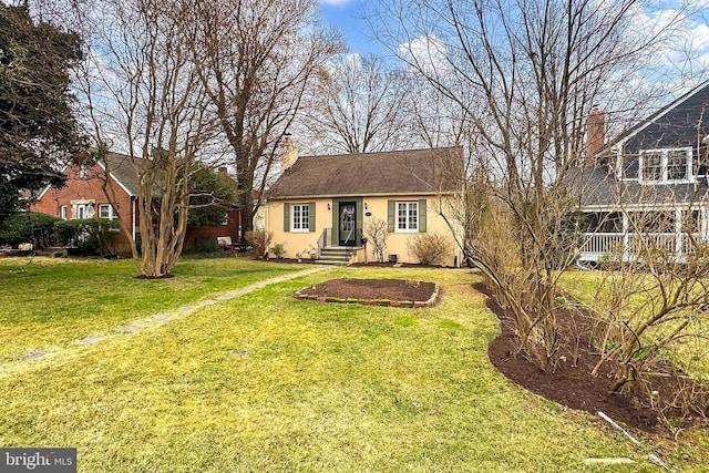 view of front facade featuring a front yard, a chimney, and stucco siding