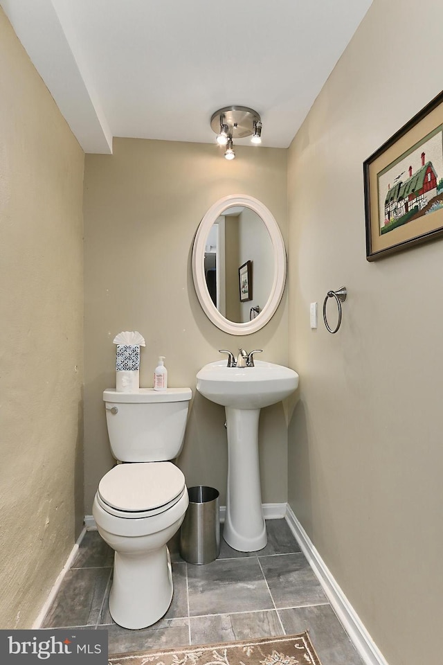 half bath featuring a sink, baseboards, and toilet