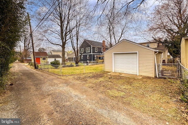 detached garage with dirt driveway and fence